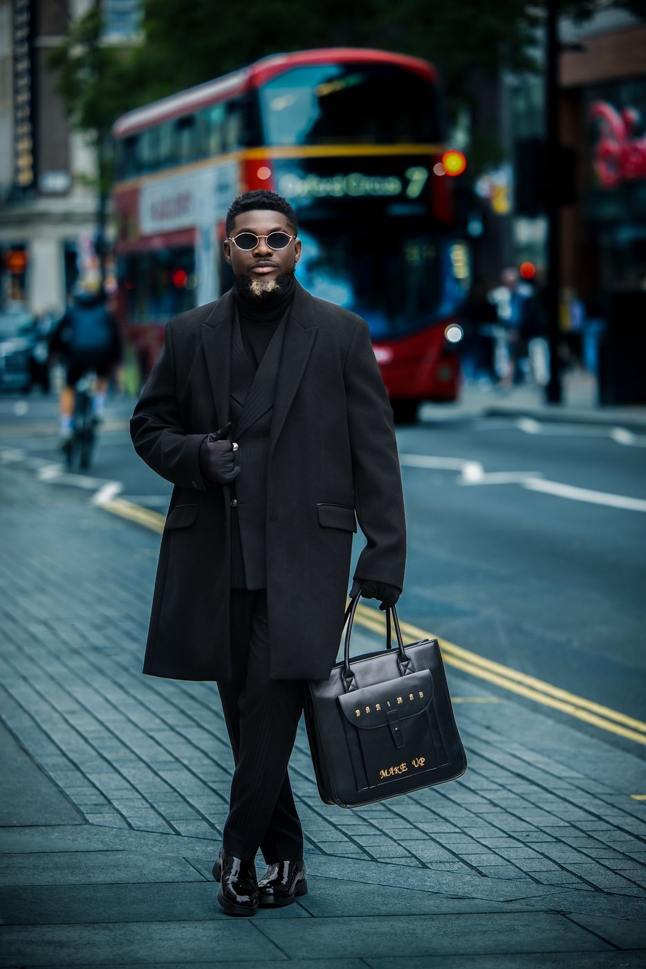 Man in a long black coat crossing Oxford Circus by a red London bus — cinematic street portrait by Rukkydidit Photography