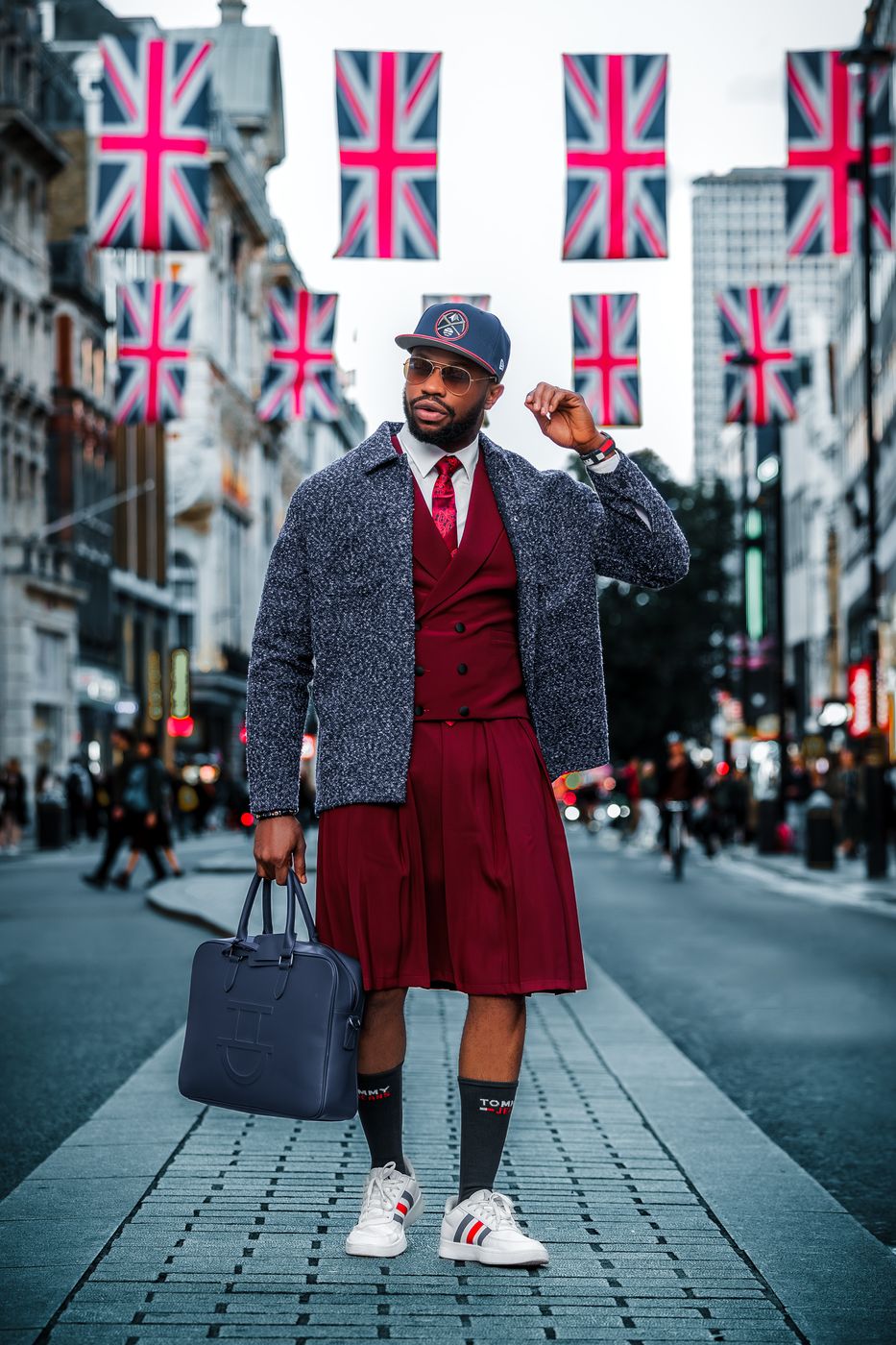 Man in a burgundy waistcoat beneath Union Jack flags on Regent Street — London street portrait