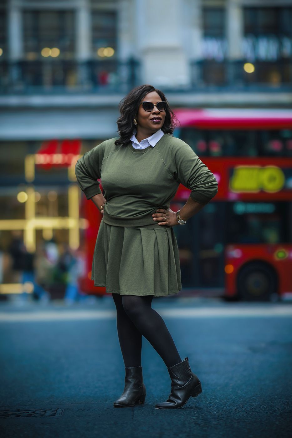 Woman in green beside a red London bus in the City of London — street portrait